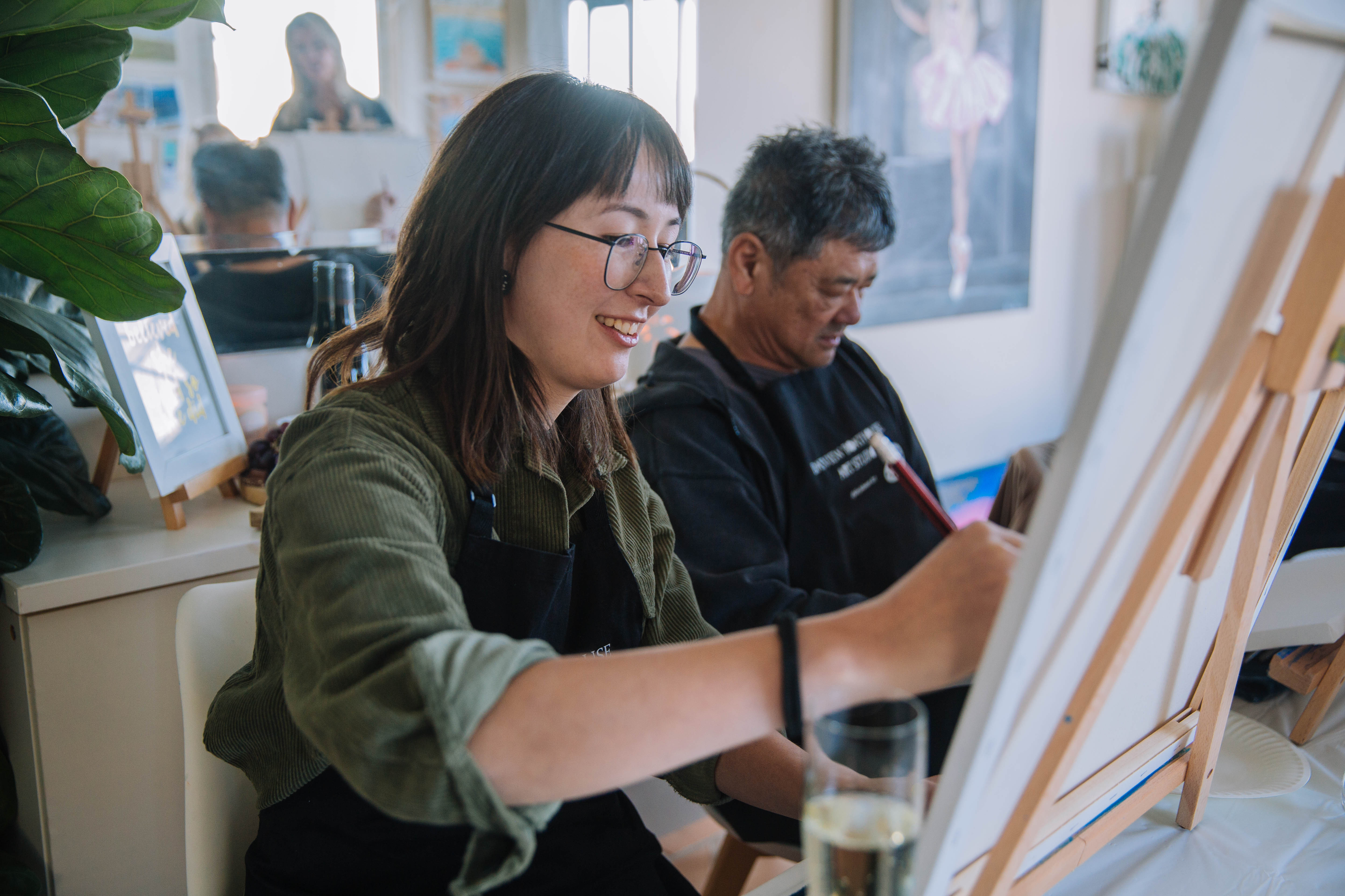 A woman laughing as she paints at an art class